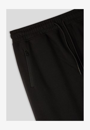 Pantaloni sportivi neri con vita elastica e cordoncino. Presentano una tasca laterale con zip e un tessuto morbido e testurizzato.