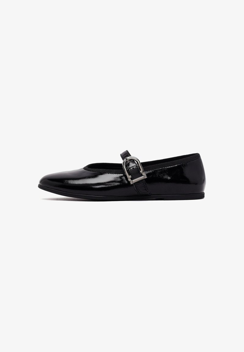 Chaussure plate en cuir verni noir avec un bout rond, une sangle élastique sur le cou-de-pied et un accent de boucle métallique sur le côté.
