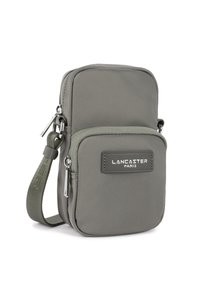 Borsa a tracolla compatta grigia con tasca frontale con zip, cinturino in tessuto regolabile e logo "LANCASTER PARIS" sul pannello frontale.