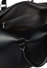 Black leather handbag with pebbled texture, top zipper opening, interior zippered pocket, and rolled leather handles with metal buckle accents.
