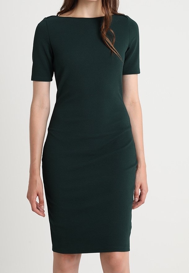 Robe ajustée vert foncé avec des manches courtes, décolleté bateau, tissu texturé et ourlet à la hauteur du genou. Les coutures ajoutent une forme subtile.