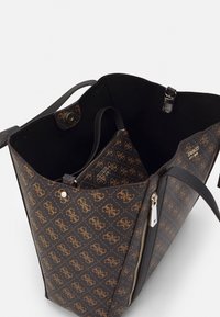Sac fourre-tout monogrammé marron et noir avec des poignées doubles et une trousse zippée assortie à l'intérieur, logo de la marque visible sur les deux.