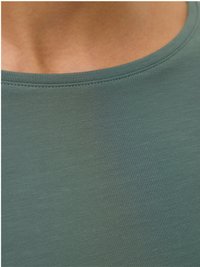 Prim-plan al gâtului și părții superioare a pieptului unei persoane care poartă un tricou din material ribatat verde, cu decolteu rotund.