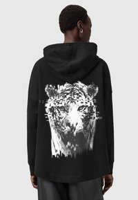 Felpa nera con una grande grafica bianca di un volto di tigre, caratterizzata da un effetto glitch. Tessuto morbido, vestibilità comoda e cappuccio con coulisse.
