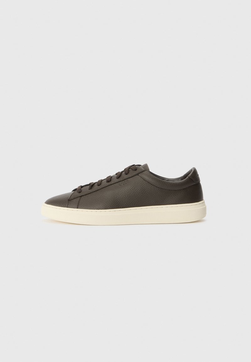 Sötétbarna bőrn sneaker texturált felülettel, fehér gumitalppal és lapos fűzőkkel. Minimalista dizájn, látható logók nélkül.