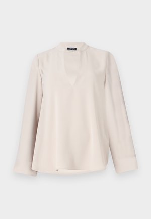 Blusa lunga color beige chiaro con scollatura a chiave e orlo arrotondato. Realizzata in tessuto morbido, presenta una vestibilità comoda e dettagli minimi.