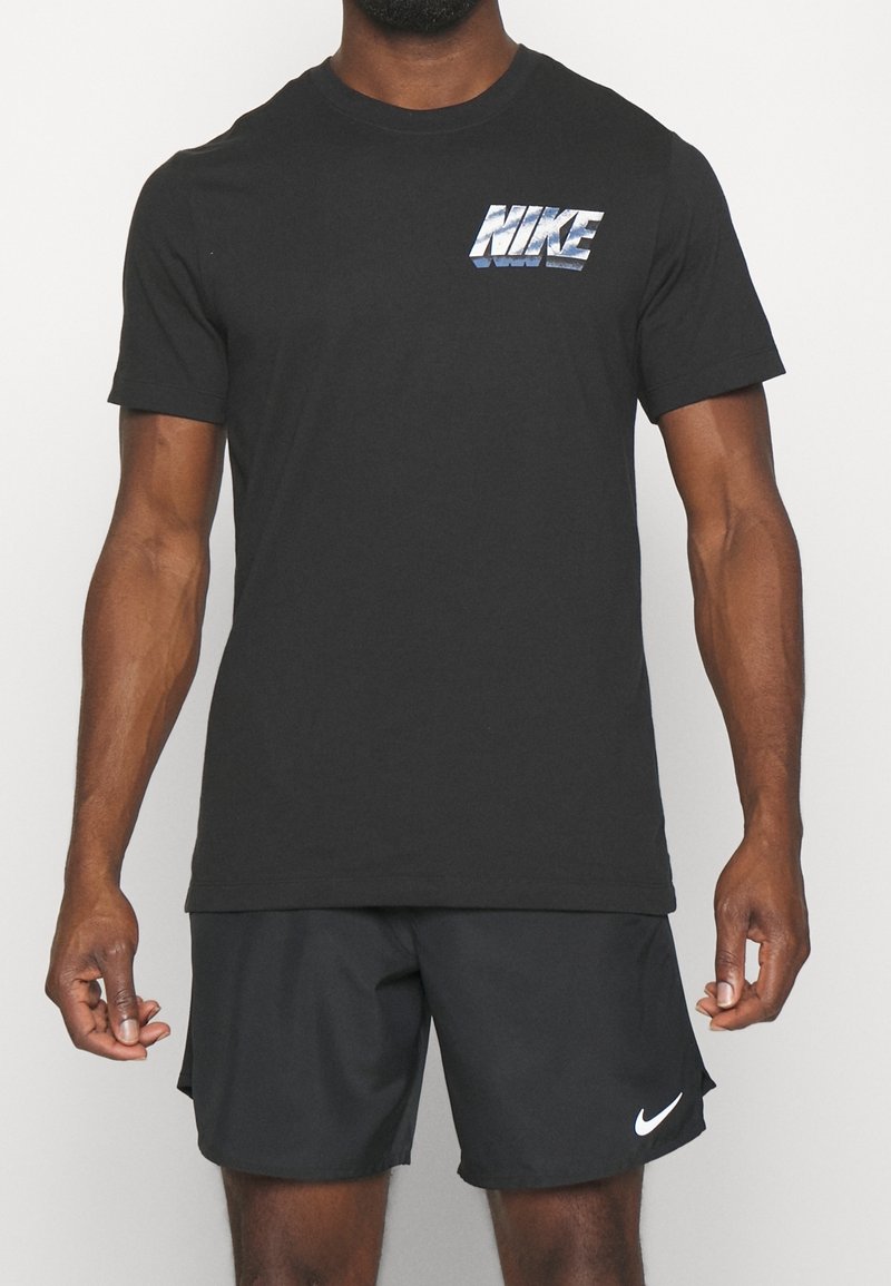 Černé bavlněné tričko s texturovaným stříbrným logem Nike. Design zahrnuje krátké rukávy a kulatý výstřih.