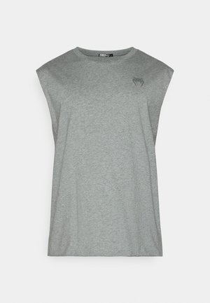 Lys grå ermeløs t-skjorte laget av mykt stoff. Har rund hals og en diskret logo på øvre venstre brystområde.