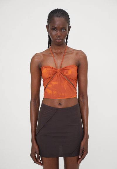 Orange strapless top with a twisted front detail, paired with a brown mini skirt featuring an asymmetrical design. Smooth, stretchy fabric.