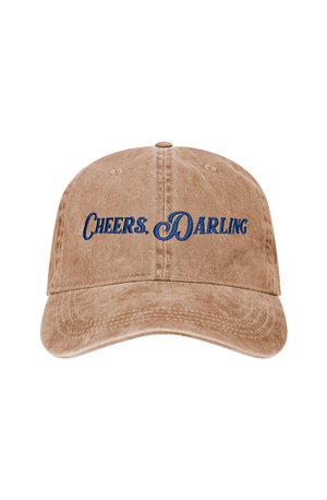 Tan cap with curved brim featuring blue embroidered text "CHEERS. DARLING." and textured fabric, designed for casual wear.