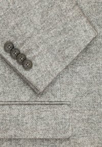 Fragment błękitnego wełnianego żakietu, charakteryzującego się teksturowanym wykończeniem, z mankietem na cztery guziki oraz kieszenią wykończoną przeszytą krawędzią.