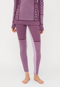 Conjunto de ropa deportiva de color púrpura con un top de manga larga que presenta diversas texturas y una malla ajustada con rayas y diseños geométricos.