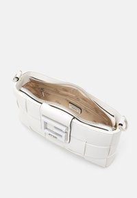 Hvid faux læder håndtaske med vævet tekstur, sølv hardware og en lynlåslukning. Indvendig har den en beige foring og flere lommer.