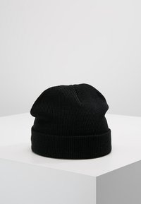 Gorro de lana negro con textura acanalada, presenta un dobladillo doblado y una parte superior holgada. Hecho de material suave y flexible.