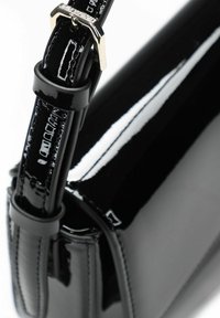 Zwarte lakkleren handtas met taps toelopende vorm, voorzien van een gewatteerde band, glanzend oppervlak en accenten van hardware in goudkleur.