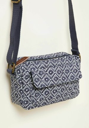 Laivastonsininen kuviollinen olkalaukku, jossa käännettävä läppä, valmistettu kankaasta. Siinä on vetoketjullinen suljentamekanismi ja säädettävä hihna, ruskeilla nahkasisustuksilla.