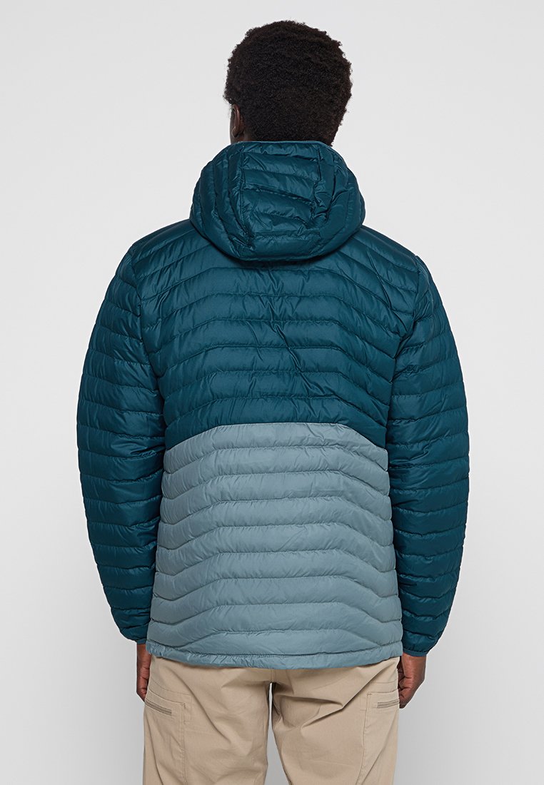 Chaqueta acolchada para hombre en color verde azulado oscuro con parte inferior acolchada en gris claro. Presenta una capucha, costuras horizontales y una textura suave.