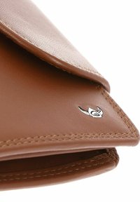 Coin de portefeuille en cuir marron avec couture détaillée et petit logo de marque argenté sur une surface lisse.