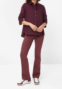 Chemise boutonnée bordeaux à manches longues, assortie à un pantalon et des baskets blanches avec des accents bordeaux. Design simple et texture lisse.