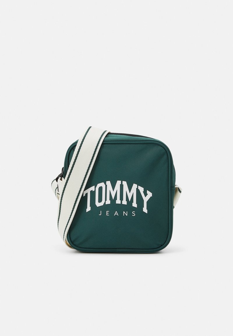 Zelená čtvercová kabelka přes rameno vyrobená z nylonu, s bílým logem "TOMMY JEANS" na přední straně a nastavitelným proužkovaným popruhem.