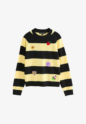Striped sweater with yellow and black colors, featuring embroidered patches: a strawberry, sunflower, smiley, heart, and cupcake.