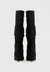 Bottes over-the-knee en suede noir avec un talon effilé, un design bouffant et une texture lisse, vues de l'arrière.