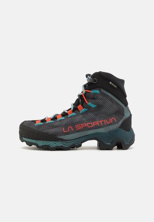Schwarze und türkisfarbene Wanderschuhe mit einer strukturierten Oberfläche, orangefarbenen Akzenten und einer robusten Sohle. Verfügt über eine verstärkte Zehenkappe und GORE-TEX-Branding.