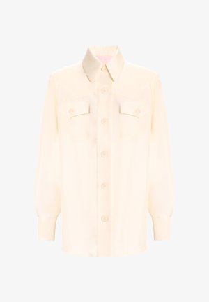 Blusa de satén crema con cuello puntiagudo, mangas largas, dos bolsillos en el pecho y cierre frontal con botones. Textura suave y corte entallado.