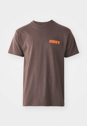 Brown cotton t-shirt with short sleeves, featuring a prominent orange "OBEY" graphic on the left chest area. Simple crew neck design.
