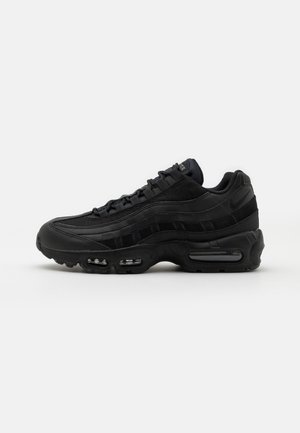 Czarny sneaker Nike Air Max 95 z warstwową konstrukcją, widoczną poduszką powietrzną w podeszwie, cholewką z siateczki i skóry oraz sznurowanym zapięciem.