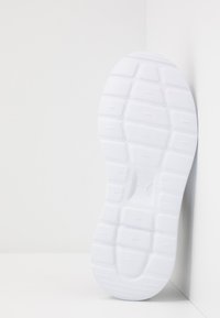White sneaker sole with textured rubber, featuring geometric patterns and a central logo indentation. Smooth edges and sturdy design.