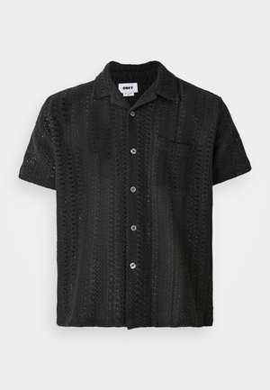 Short-sleeve black crochet shirt with a relaxed fit, featuring a button-up front, single chest pocket, and textured open pattern.