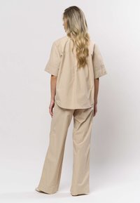 Beige oversize t-shirt med kort ärm och matchande byxor med vida ben. Mjukt tyg med slät yta, med en minimalistisk design utan synliga detaljer.