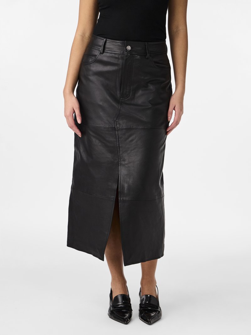Zwarte leren midi rok met een rechte snit, een split aan de voorkant en zijzakken. Soepele textuur met zichtbare stiksels en een metalen knoopdetail.