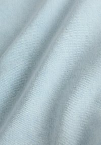 Tissu denim doux bleu clair avec un fin motif de tissage diagonal et de légers plis.