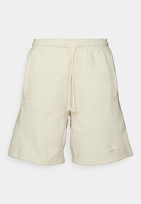 Pantalones cortos de sudadera color crema confeccionados en una tela suave, con una cintura elástica y cordón ajustable, bolsillos laterales y un pequeño logo decorativo.