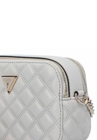 Sac à main en simili cuir gris clair matelassé avec quincaillerie dorée, fermeture à double zip et accent de logo triangulaire.