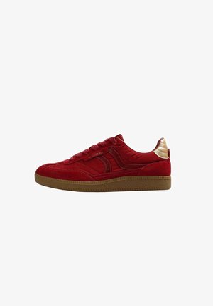 Sneaker in suede rosso con un accento oro sul tallone, caratterizzata da un design testurizzato e una suola in gomma naturale, chiusa con lacci piatti.