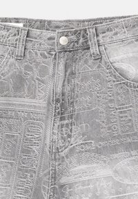 Jeans in denim grigio con intricate trame testurizzate e dettagli cuciti, con chiusura a bottone metallico in vita.