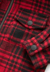 Röd och svart rutigt flanelljacka med zippered front, knäppt ficklock och textil med synlig väv.