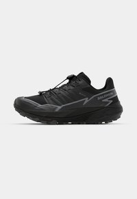 Zwarte trailrunningschoenen met een gestructureerde bovenkant, reflecterende accenten en een robuuste zool, voorzien van een vetersysteem voor een veilige pasvorm.