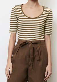 Pruhované hnědé a krémové tričko s krátkým rukávem a kulatým výstřihem, spárované s hnědými kalhotami s vysokým pasem a detailem vázačky v pase.