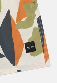 Shorts multicolori con un mix di motivi a foglia arancioni, verdi e blu su uno sfondo crema, con un'etichetta nera "JACK&JONES".