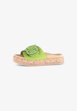 Sandales à glissière en daim vert avec une semelle en liège épaisse, un grand accent à double boucle et une doublure intérieure lisse. Détails texturés sur la semelle.