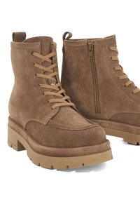 Brown suede lace-up boots with chunky rubber soles and side zipper on white background, shown in close-up pair view.