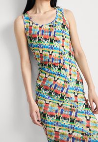 Farbenfrohes, ärmelloses Kleid mit einem lebhaften abstrakten Muster in mehreren Farbtönen, darunter Blau, Rot, Grün und Schwarz auf einem hellen Hintergrund.
