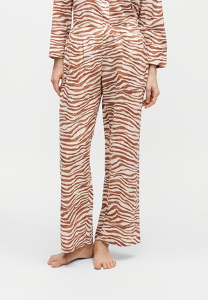 Pantaloni larghi con strisce zebrate marroni e bianche, indossati a piedi nudi, abbinati a una maglia a maniche lunghe coordinata, mostrati dalla vita ai piedi.