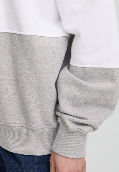 Felpa a blocchi di colore grigia e bianca con polsini e orlo a costine, caratterizzata da una vestibilità comoda e una texture morbida.