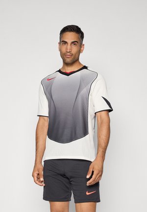 T-shirt de sport Nike avec un design dégradé allant du gris au blanc, bord noir et lignes courbes. Assorti à un short sombre avec un logo rose.