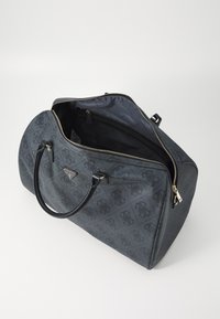 Borsa da viaggio in pelle grigia scura con motivo della logo impressa, manici neri, finiture in oro e apertura con zip che rivela un interno nero.